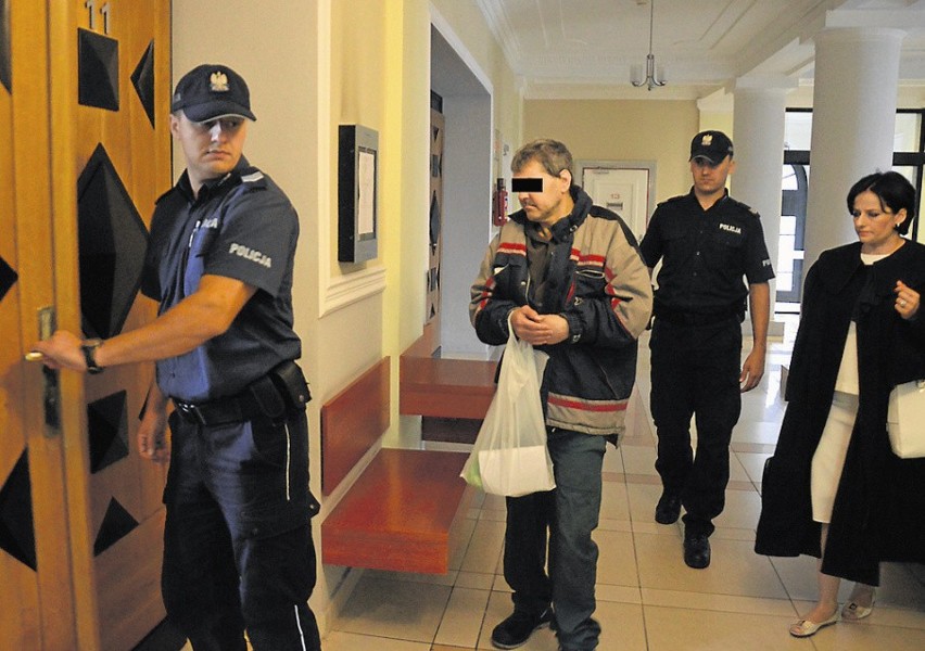 Oskarżony Andrzej K. w konwoju policyjnym idzie na rozprawę...