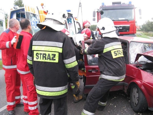 Strażacy pomagali kierowcy i pasażerce golfa wydostać się z samochodu.