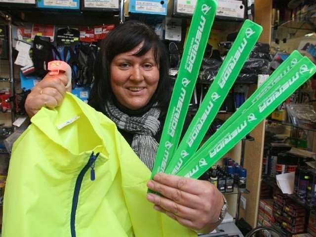Małgorzata Piątek, prowadząca w Kielcach sklep rowerowy, prezentuje odblaskowe opaski i kamizelkę oraz małą lampkę, którą można przyczepić do plecaka czy czapki.