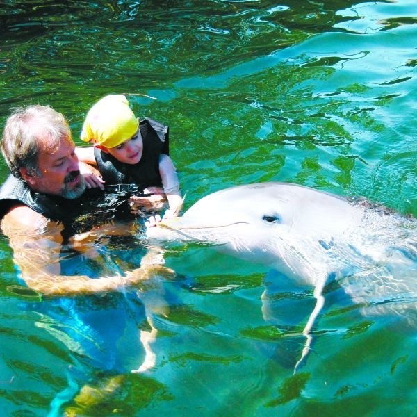 Kubuś w czasie zajęć ze swoim terapeutą Jackiem i delfinem Fiji. Dotykanie delfina, pływanie z nim w wodzie, pozwalało na poznanie przez chłopca nowych bodźców i poprawę funkcjonowania chłopca na co dzień.