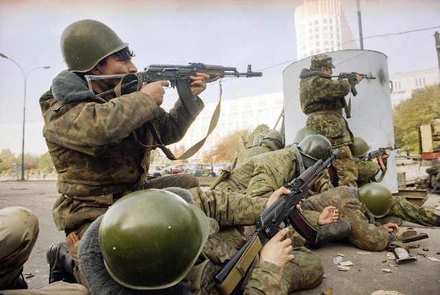 Żołnierze armii rosyjskiej strzelają z pistoletów maszynowych, aby osłaniać innych żołnierzy, przed budynkiem parlamentu 4 października 1993 r. w Moskwie