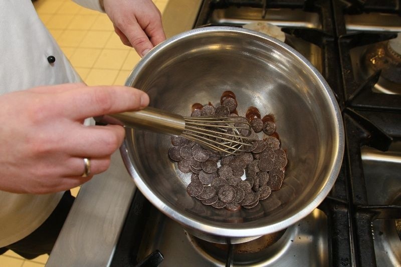 Do metalowej miski wkładamy pokruszoną czekoladę i pocięte...