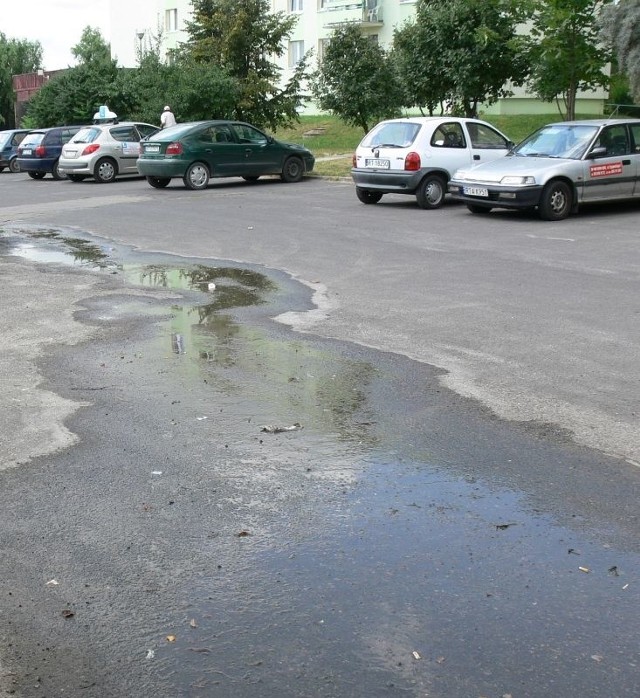 Na parkingu przy ulicy Kopernika woda z pękniętej rury spokojnie spływa do studzienki kanalizacyjnej.