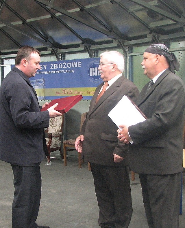 Wiceminister Artur Ławniczak (z lewej)  składa gratulacje Zygmuntowi Krzemińskiemu (w środku), twórcy firmy, i prezesowi Janowi Krzemińskiemu.