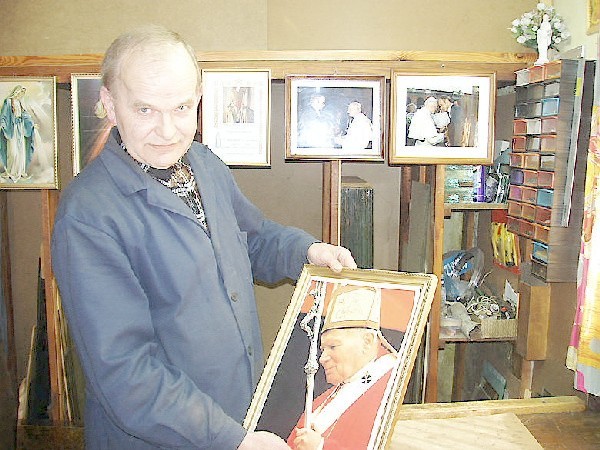 Pan Antoni Chyła w swoim warsztacie  szklarskim oprawia zdjęcie Jan Pawła Ii.