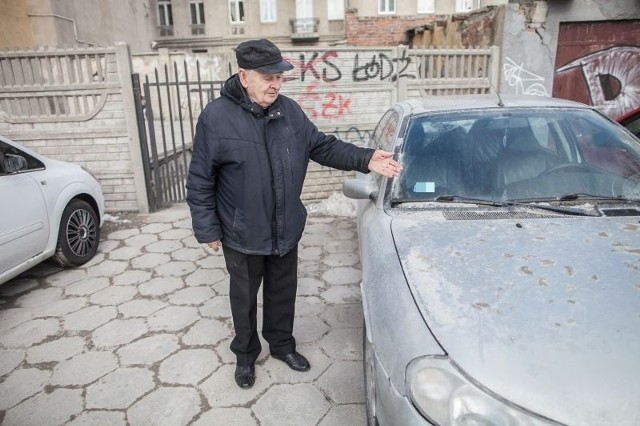 Eugeniusz Mikołajewski, mieszkający na tyłach dawnego hotelu, pokazuje zabrudzone samochody.