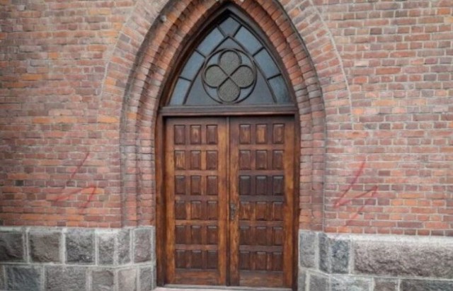 Na ścianach przed drzwiami wejściowymi kościoła namalowano farbą symbole strajku kobiet (błyskawice).