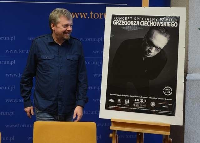 Dyrektor Akademickiego Centrum Kultury i Sztuki Od Nowa Maurycy Męczekalski przy plakacie koncertu pamięci Ciechowskiego