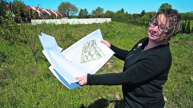 Katarzyna Wasilewska pokazuje plany dotyczące nowego osiedla domów wielorodzinnych w rejonie ul. Franciszkańskiej w sąsiedztwie domków (domki widać na zdjęciu w tle, po lewej stronie, a widoczne jasne ogrodzenie, to właśnie teren przyszłego placu budowy domów wielorodzinnych)