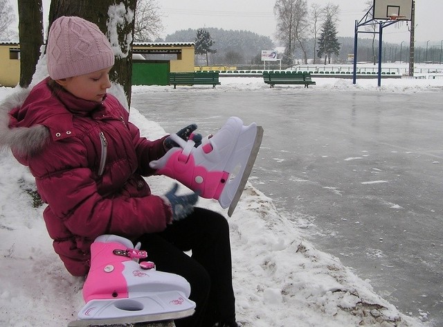 11-letnia Julia przygotowuje się do jazdy na łyżwach. 