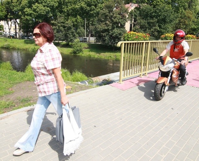 Młodzi kierowcy jadą skuterami po chodniku przy ul. Zamkowej.