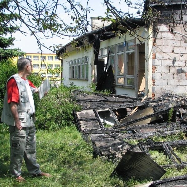 Alfred Martyniuk, pokazuje rozrzucone resztki spalonego azbestu, z którego zbudowane były ściany i dach baraku przy ulicy Targowej w Tarnobrzegu.