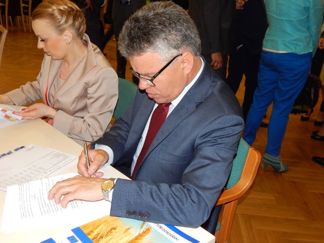 Burmistrz Jacek Sauter podpisuje umowę, dzięki czemu gmina dostanie pieniądze na remonty dróg.