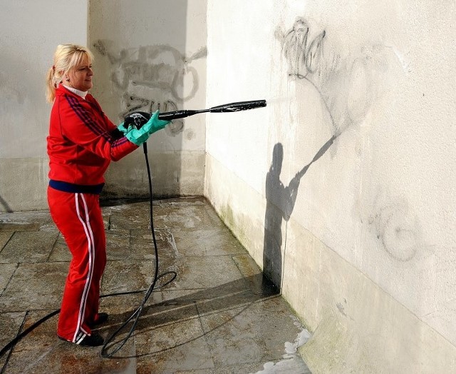 Ewa Goszczyńska, pracownica Stargard Borst czyści mur Zamku z graffiti.
