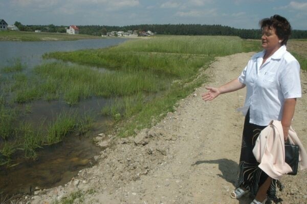 Krystyna Kołomańska pokazuje źle wykończony przepust wodny znajdujący się przy drodze do jej pola i rozmytą drogę.