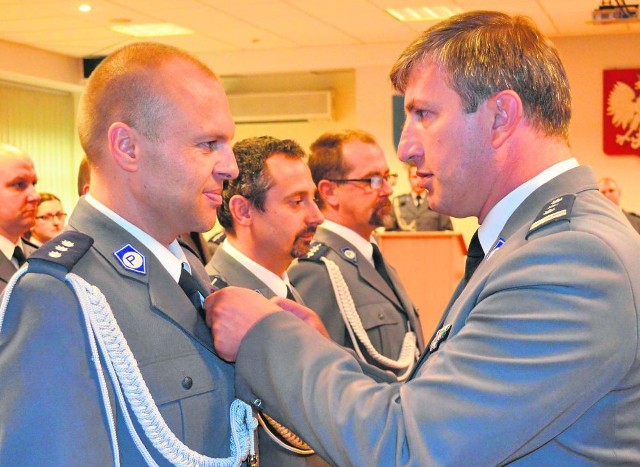 Komendant Fabisiak (z prawej) wręcza policjantom medale