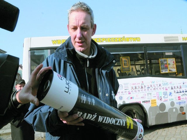 Sławomir Piotrowski z magiczną tubą na tle autobusu użyczonego akcji przez MZK.