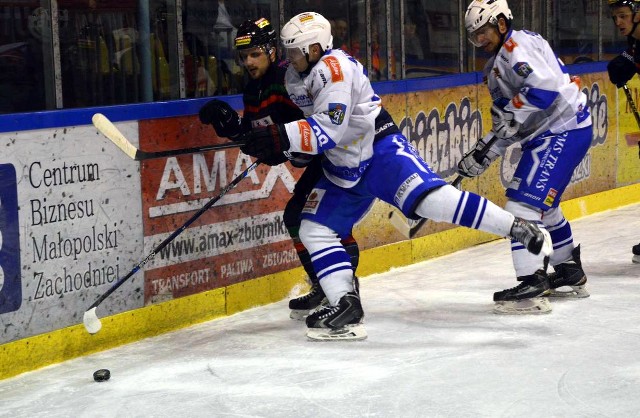 W trzeciej tercji meczu w Oświęcimiu trzeszczały bandy. Mateusz Adamus (Unia) atakuje tyskiego obrońcę Mateusza Bryka. Z tyłu Damian Piotrowicz (Unia).