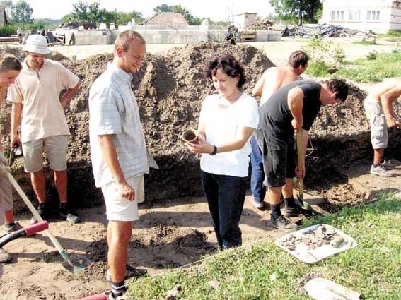 Nadzorująca badania inspektor ochrony zabytków Małgorzata Schild i archeolog Paweł Jarosz oglądają kolejne znalezisko - gliniany czerpak z epoki brązu będący elementem wyposażenia jednego z grobów.