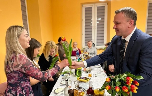 Poseł Michał Cieślak wręcza kwiaty paniom podczas Dnia Kobiet w Raczycach w gminie Gnojno.