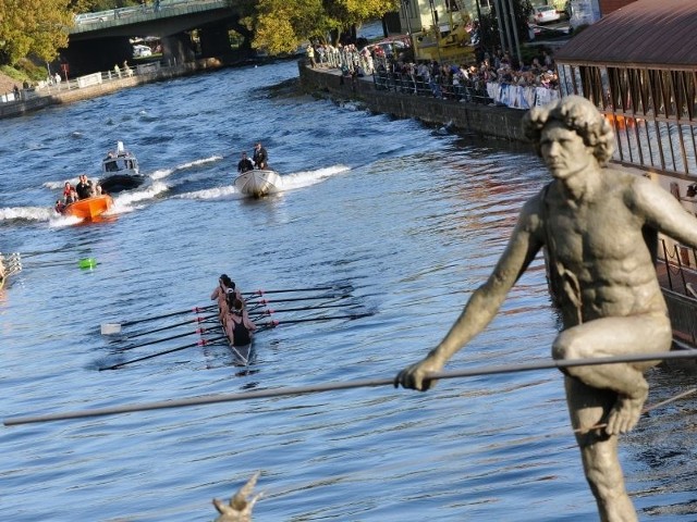 Zmagania wioślarzy (tu brytyjskich osad) przy pięknej pogodzie i sporej liczbie kibiców z zainteresowaniem obserwował także &#8222;Przechodzący przez rzekę&#8221;