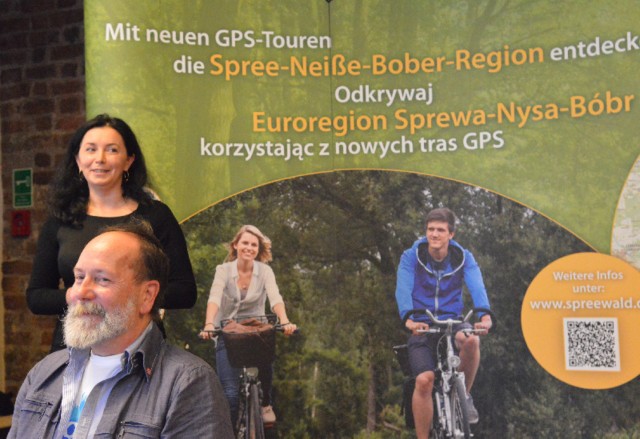 Jolanta Tenner-Imbierska z CottbusService i Eberhard Nahly z biura nadburmistrza Cottbus obok reklamy tras GPS po polskiej i niemieckiej stronie.