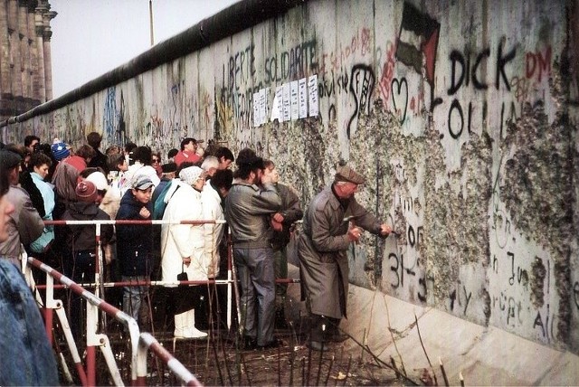 Mieszkańcy Berlina Zachodniego przy mocno zniszczonym murze w pobliżu Reichstagu w końcu 1989
