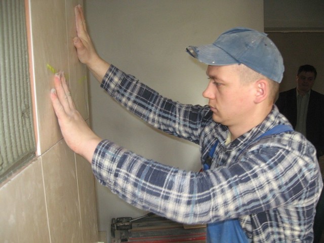 Robotnik Marcin Honkisz pracuje przy ścianie jednego z pomieszczeń odnawianej komendy w Strzelcach.