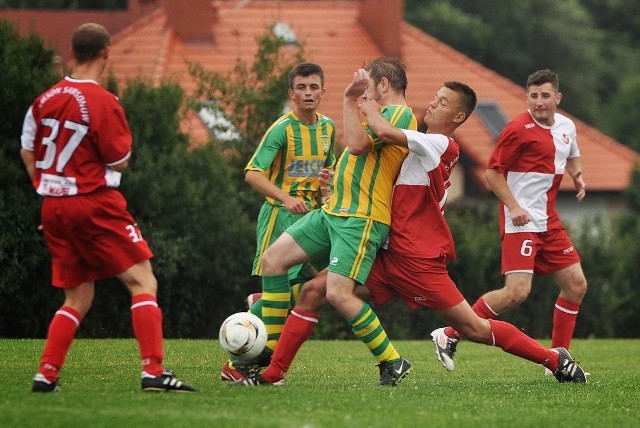 Mateusz Górecki w barwach Samsona Samsonów (biało-czerwony strój) walczy o piłkę z zawodnikiem Grodu Ćmińsk. Prezes klubu wciąż występuje w jego barwach na boisku.