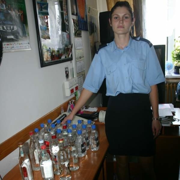 Katarzyna Małecka ze skarżyskiej policji pokazuje butelki z nielegalnym alkoholem, znalezione w mieszkaniu 57-latki.