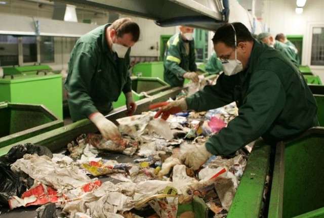 Pracownicy segregują śmieci, oddzielając od nich poszczególne surowce.