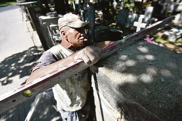 Waldemar Szafrański jest jednym z pracowników, którzy remontują będące w złym stanie ogrodzenie cmentarza przy ulicy Antczaka