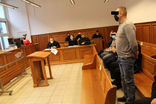 Wojciech C. (stoi) oraz Krzysztof W i Paweł L. na sali rozpraw krakowskiego sądu w konwoju policyjnym