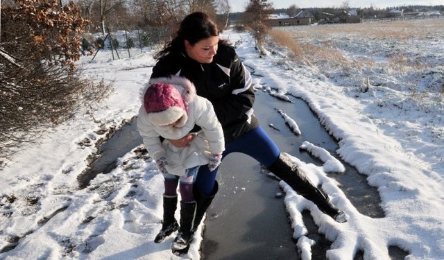 Katarzyna Dobiosz z córeczką Amelką pokazuje, jak dziurawa jest droga do jej posesji 