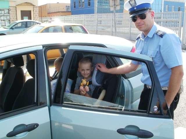 Jedno z obdarowanych maskotką dzieci  wraz z policjantem, biorącym udział w akcji