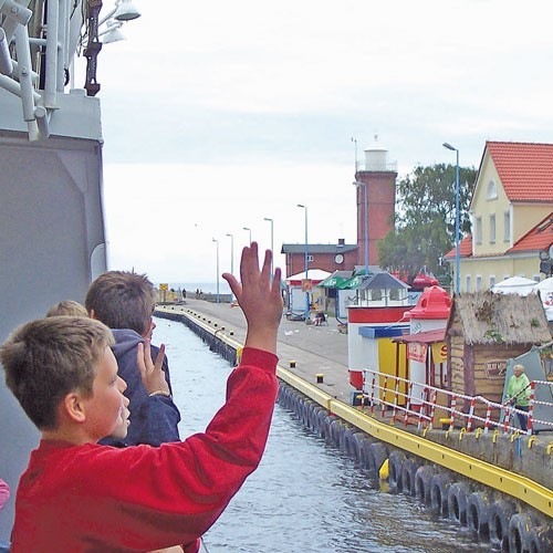 Mali pasażerowie machają na pożegnanie nielicznym porannym turystom koło latarni morskiej w Darłowie.