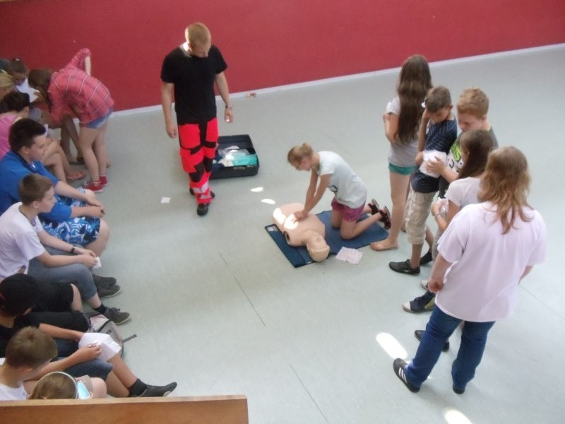 Ratownicy medyczni uczą dzieci udzielania pierwszej pomocy....