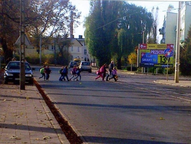 Fotografia przedstawia grupę dzieci maszerujących przez ulicę Dworcową, tuż u jej zbiegu z Moniuszki. W tym miejscu - jak słusznie zauważa "Rodzic&#8221; - nie ma oznaczonego przejścia dla pieszych.