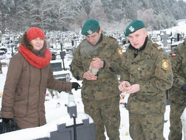 Uczniowie klasy mundurowej zapalają znicze na cmentarzu w Hucie Krzeszowskiej.