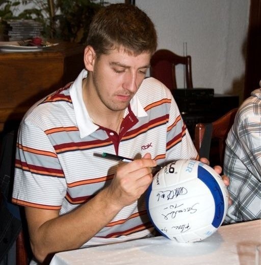Wojciech Kaźmierczak podpisuje pamiątkową piłkę.