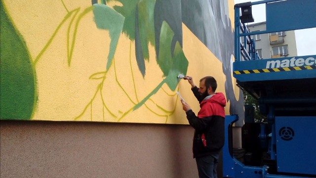 Arkadiusz Andrejkow przy końcu pracy nad muralem Marcelego Siedlanowskiego na ścianie bloku w Stalowej Woli