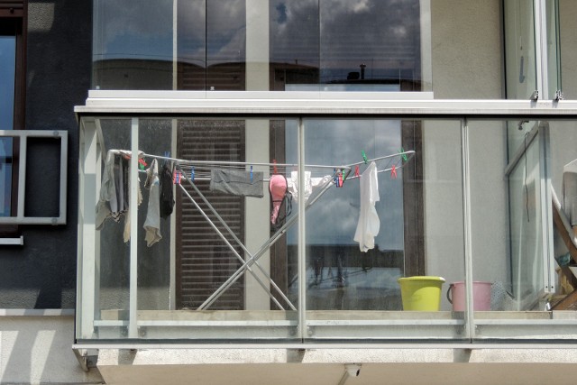 Wywieszanie prania przez kobietę w krótkiej koszulce i spodenkach bywa powodem waśni sąsiedzkich.