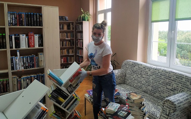W wypożyczalni dla dorosłych, zaopatrzona w rękawiczki i maskę, wita czytelników bibliotekarka Magdalena Stormowska