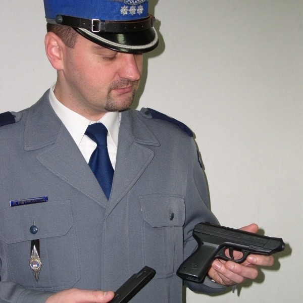 Komisarz Rafał Pietrkiewicz pokazuje pistolet - jak się okazało odpustową zabawkę na kulki - który odebrano agresorowi.