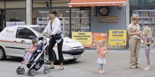 Niektóre auta stoją w bocznych uliczkach, inne jeżdżą przez środek deptaka