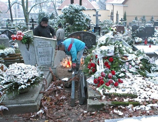 Po interwencji rodziny pracownicy firmy pogrzebowej porządkują nagrobek. 