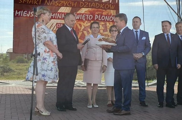 Burmistrz Staszowa Leszek Kopeć odbiera okazały bochen chleba z rąk starostów dożynek.
