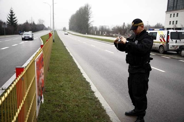 Młodszy strażnik Tomasz Prymaczek fotografuje plakat bezprawnie zawieszony na płotku na ul. Mickiewicza