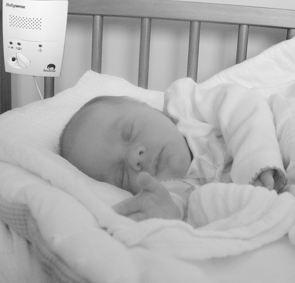 Monitor kontroluje oddech śpiącego niemowlęcia. Gdy czujnik go nie wykryje, włącza się alarm.