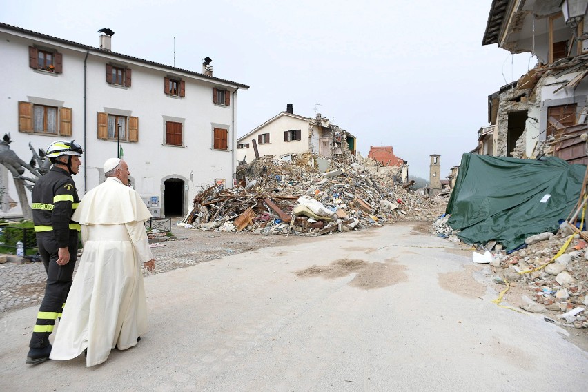 Papież Franciszek wraz ze strażakiem oglądają zawalone domy.